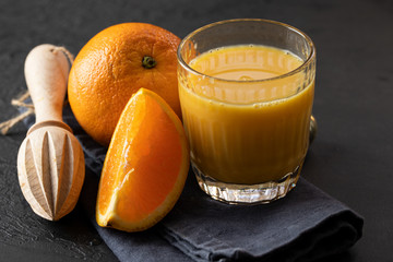 Orange juice, orange fruit  and wood citrus squeezer on dark background. Making natural juice concept.Close up