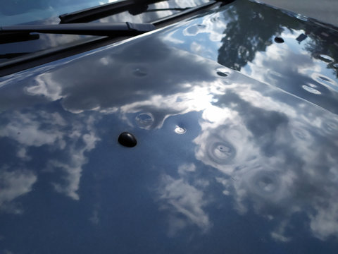 Motorhaube eines grauen PKW mit Hagelschaden zeigt nach extremem Wetter mit Sturm und einem Hagelschauer viele Dellen und Beulen in der Motorhaube f&uuml;r die Versicherung