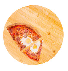A quarter and one slice of delicious pizza with beef sausages, eggs and bacon on a wooden round platter isolated on white background, top view