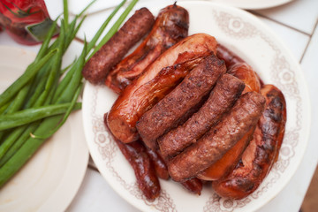 ready-made meat sausages chimpchichi lie on a white plate nearby lies a green onion