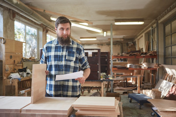 Möbelbauer mit Checkliste in der Tischlerei