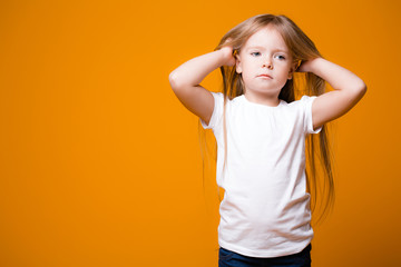 adorable girl 4-6 years old posing at camera isolated. shy little caucasian child. orange background