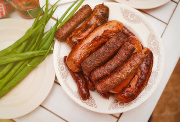 ready-made meat sausages chimpchichi lie on a white plate nearby lies a green onion