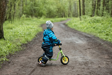 Obraz premium Little boy riding runbike on the forest road