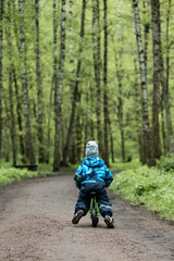 Little boy riding runbike on the forest road