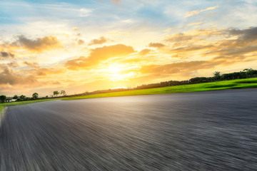 Fototapeta premium Fast moving asphalt highway and green forest at sunset.
