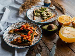 Spinach and avocado toasts with red bell pepper, fresh squeezed orange juice on dark wooden board. Healthy Breakfast concept.