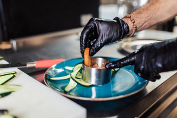 Professional chef in restaurant kitchen preparing delicious meal with meat and vegetables.