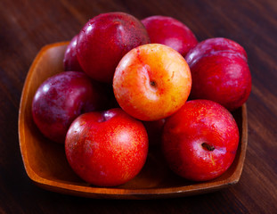 Close-up of fresh juicy red plums on wooden surface