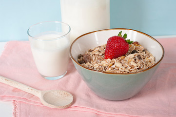 Oatmeal breakfast, muesli in ceramic bowl with strawberries. Glass of milk. Healthy food. Close up.