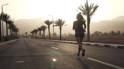 Fit brunette girl jogging on the morning highway in the tropics