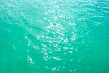 Summer background - turquoise water surface with small waves in the sun light