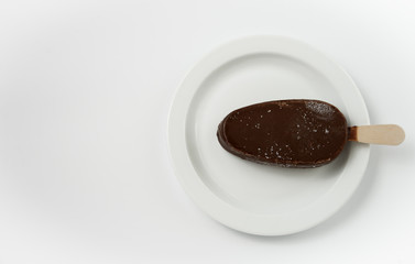 ice cream in black chocolate on a white plate  view from above 
