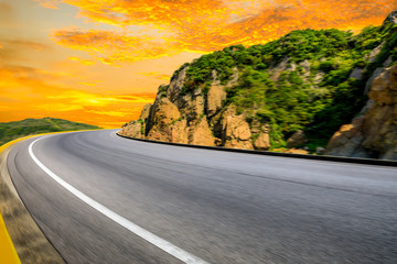 Motion blurred mountain road,asphalt roads and mountains with sky clouds at sunset.