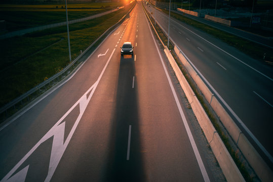 A Car Casting A Shadow On A Fast Road