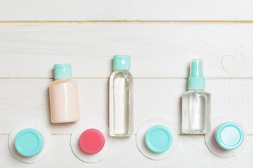 Top view composition of small travelling bottles and jars for cosmetic products on wooden background. Facial skin care concept with copy space for your design