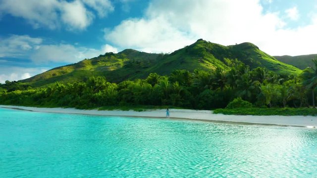 Girl walking on perfect tropical island beach during bright morning light, drone