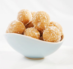 Dessert Baked balls with coconut Apricot Cashew Laddu in a white bowl isolated. rum balls in coconut. Coconut balls. Flower, baked.
