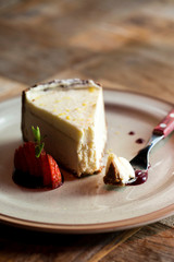 Dessert Cheesecake on a plate with fork and sliced strawberry, side view. piece of cheesecake on a plate and a fork. 
