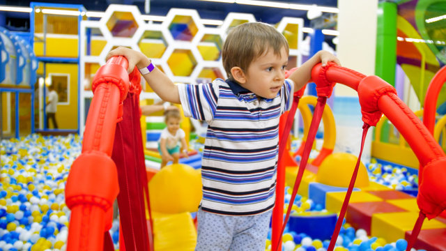 Portrait of cute little boy balancing on balancing board in children playroom at shopping mall