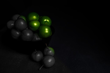Close-up macro fresh green sour plum. Greengage on dark background.  Colorful, black and white.  Creative concept.