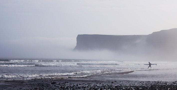 Surfer entering misty waves