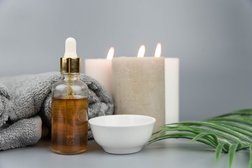 Obraz na płótnie Canvas Towel with aromatic candles and bottle with natural organic oil essence serum. Aromatherapy and beauty. Concept set of harmony, balance and meditation, spa, massage, relax, beauty spa treatment.