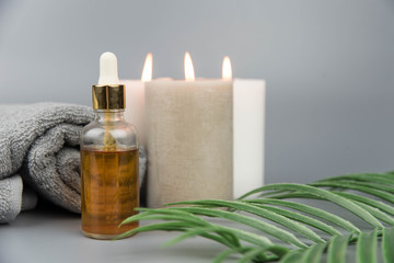Fototapeta na wymiar Towel with aromatic candles and bottle with natural organic oil essence serum. Aromatherapy and beauty. Concept set of harmony, balance and meditation, spa, massage, relax, beauty spa treatment.