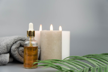 Fototapeta na wymiar Towel with aromatic candles and bottle with natural organic oil essence serum. Aromatherapy and beauty. Concept set of harmony, balance and meditation, spa, massage, relax, beauty spa treatment.