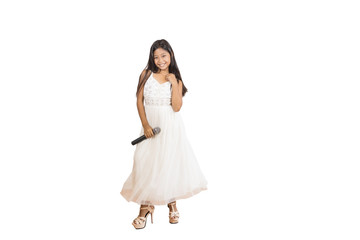 Portrait of a cute Asian elementary school girl with long hair wearing a white evening dress with a microphone used for singing. An isolated image with white background