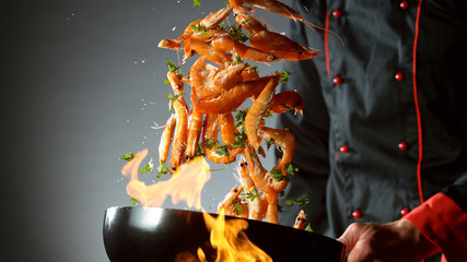 Closeup of chef throwing prawns from wok