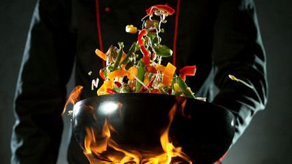 Closeup of chef throwing vegetable mix from wok