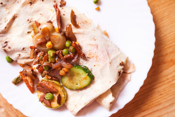 home-cooked shaverma. Sausage, cucumber, grilled vegetables lie on a pita