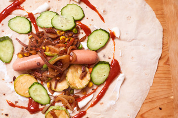 ingredients for home-cooked shaverma. Sausage, cucumber, grilled vegetables lie on a pita