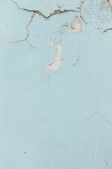 Texture of cracked wall with light blue paint, background or backdrop of abandoned building exterior.