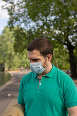 Photo of a young and attractive man wearing a face mask walking in the park