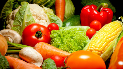 Closeup photo of big assortment of resh vegetable from garden over black background. Background for healthy food and GMO free products.Diet nutrition and fresh vegetables. Vegan and vegetarian