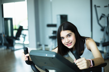 Fit young girl using exercise bike at the gym. Fitness female using air bike at gym.