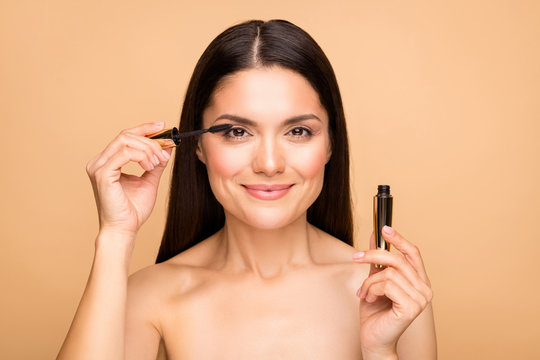 Closeup photo of mature latin naked lady model holding eyelash bottle applying one eye making night makeup preparing for date isolated beige pastel color background