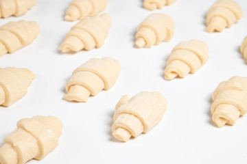 Close up studio shot of semi-finished frozen ready to cook croissant isolated on white background. Uncooked traditional french pastry. Copy space, top view.