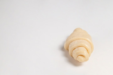 Close up studio shot of semi-finished frozen ready to cook croissant isolated on white background. Uncooked traditional french pastry. Copy space, top view.
