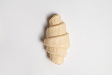 Close up studio shot of semi-finished frozen ready to cook croissant isolated on white background. Uncooked traditional french pastry. Copy space, top view.