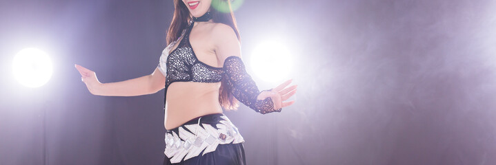 Young woman belly dancer in exotic dress with gold, dancing tribal fusion dance in studio. Copy space, close-up.