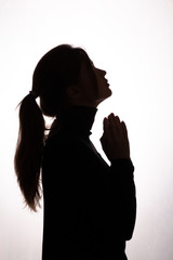 silhouette girl raised her head up asking for help on white isolated background, young woman in black clothes praying