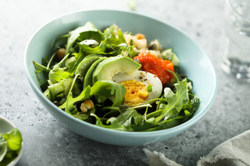 Healthy quinoa bowl with arugula, egg and avocado