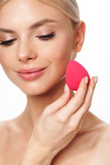 Image of happy shirtless woman using cosmetic sponge and smiling