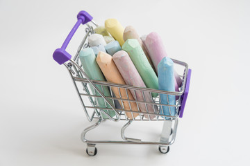 There are colored crayons in the shopping basket. The concept of buying and choosing. A variety of colors.