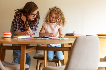 Mother helps her daughter with homework assignment .	
