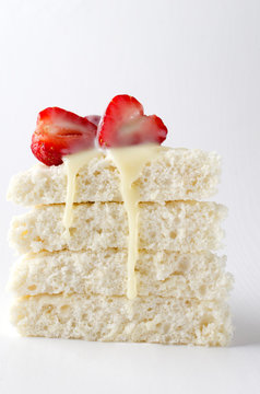 Vertical image.Piece of biscuit with juicy strawberries and milky topping on the white background