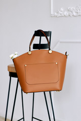 Women's brown bag hanging on a chair. White background. Studio. Vertically.